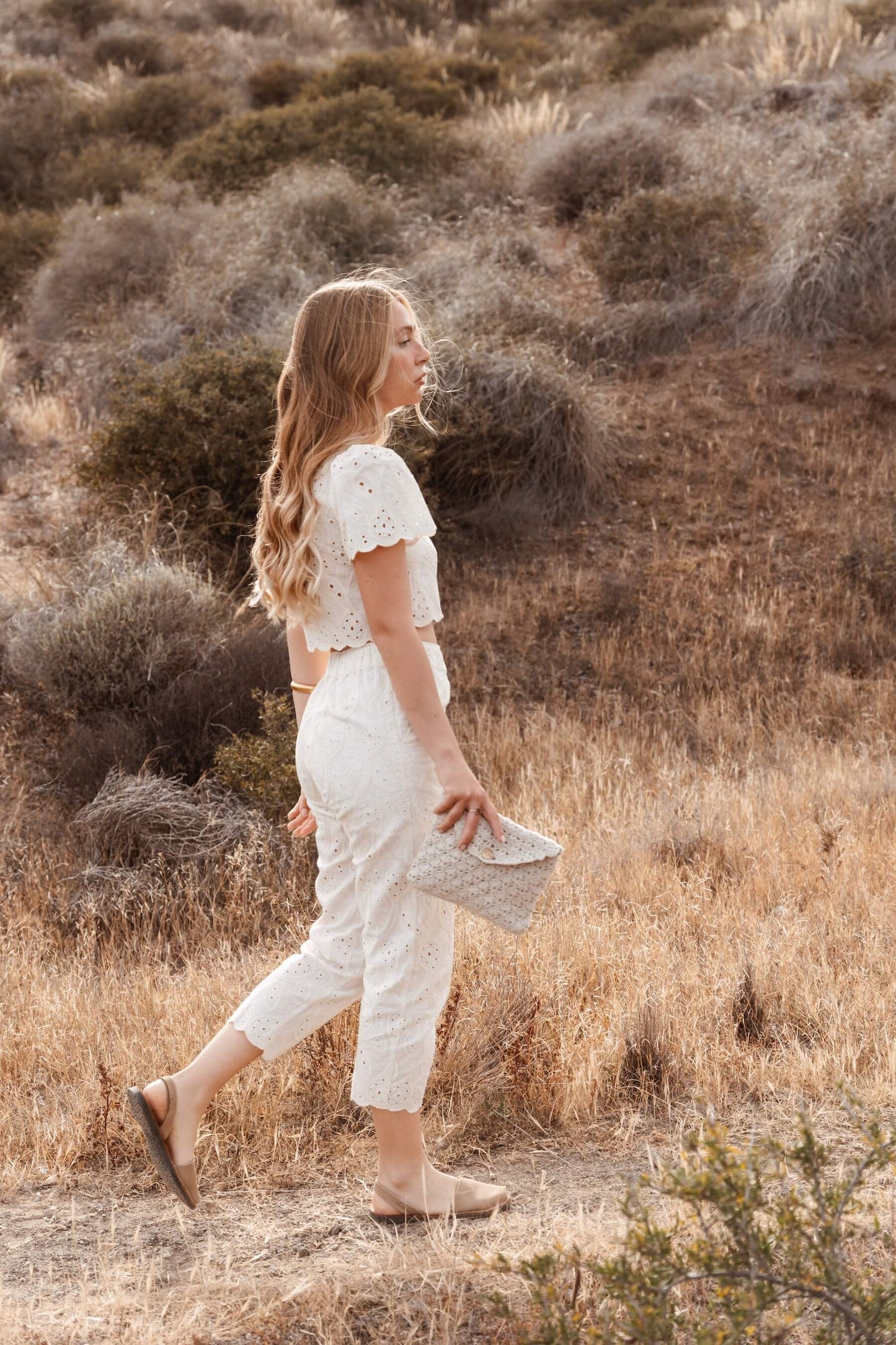 Mujer caminando en la naturaleza con el neceser de crochet SALITRE, diseño atemporal de Cabori con alma mediterránea