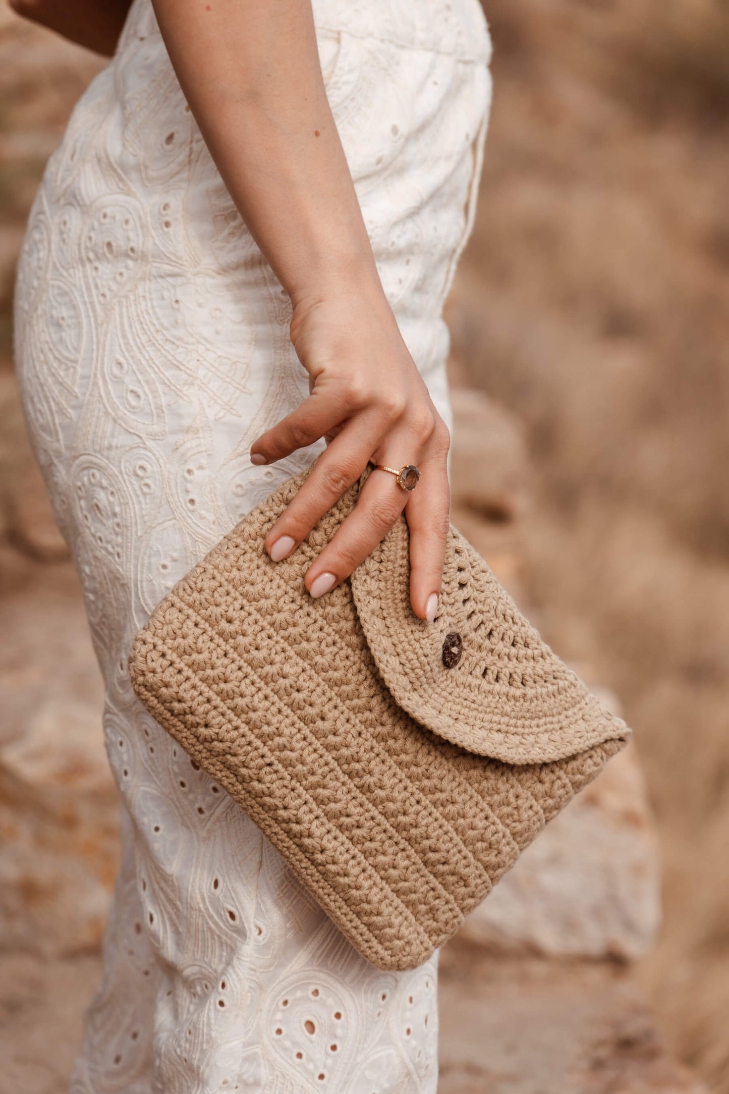 Detalle en movimiento del neceser CALIMA de crochet, con cierre de solapa y botón de coco natural