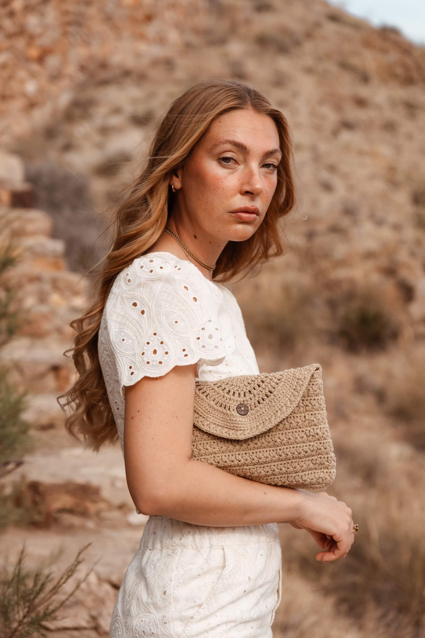 Mujer con neceser CALIMA de Cabori, accesorio artesanal en tono arena suave, inspirado en paisajes del Cabo de Gata