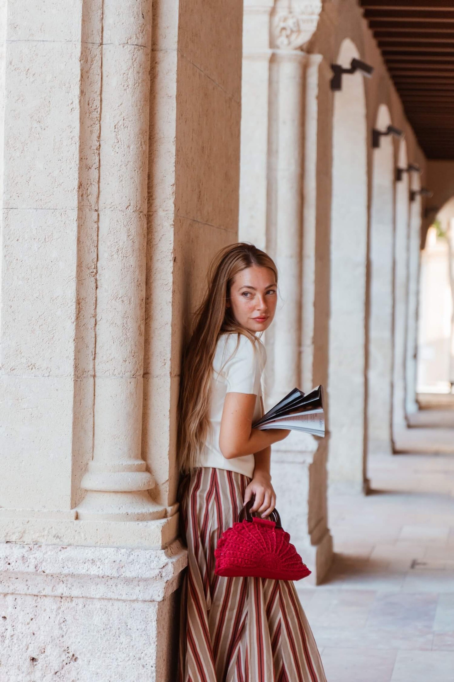 Mujer sosteniendo el bolso artesanal Cabori Buganvilla en crochet granate con asas de madera, hecho a mano en Almería.