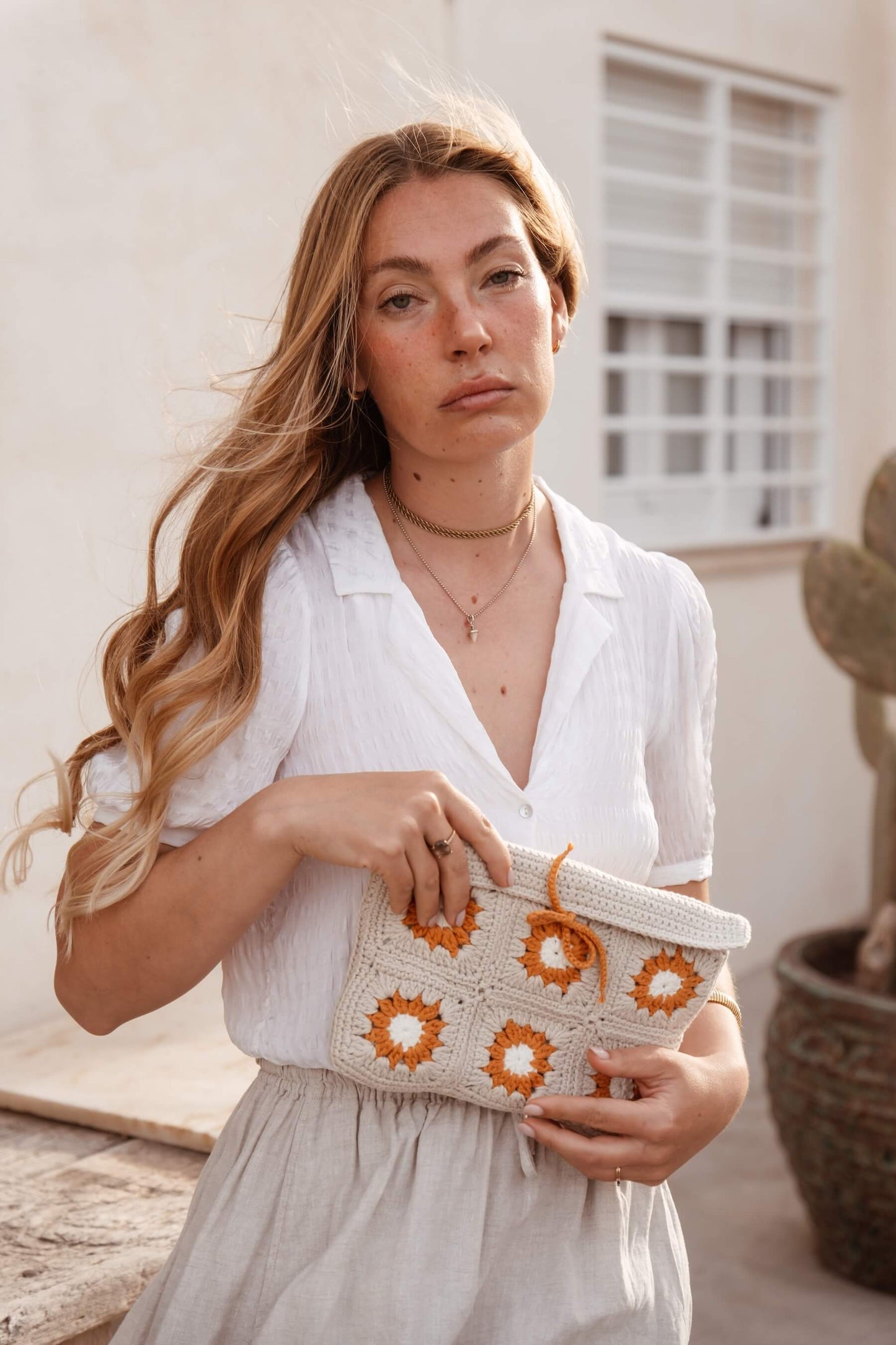 Mujer llevando neceser Solano de crochet en pueblo mediterráneo