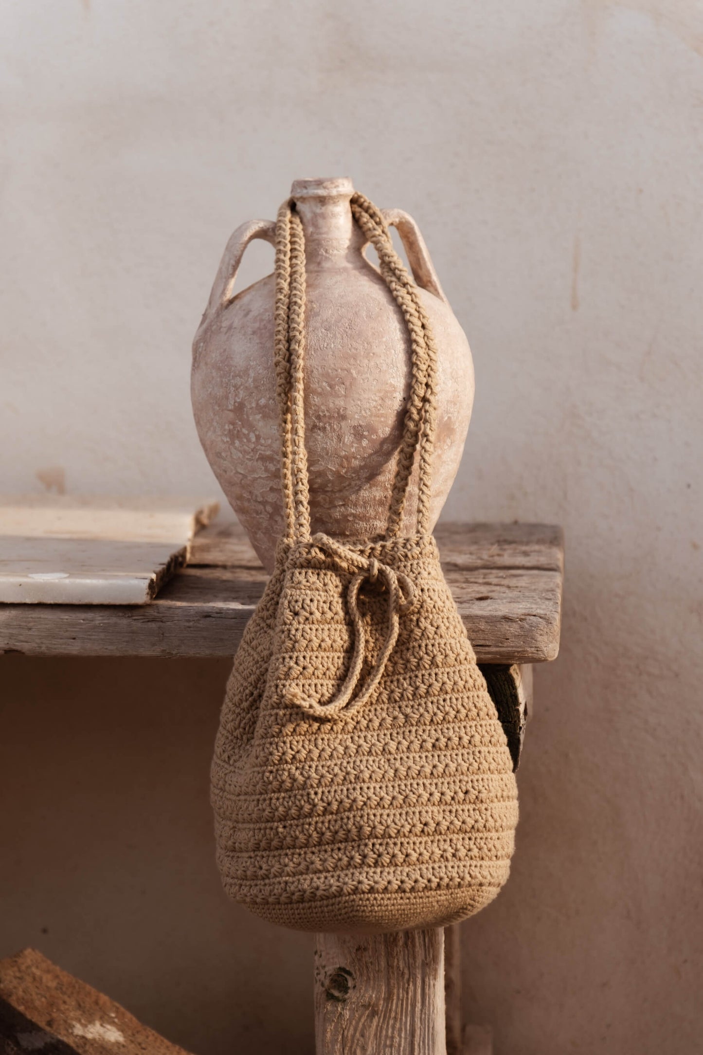 Bolso CALIMA tipo bombonera colgado de ánfora, tejido a mano con cordón ajustable y textura natural en crochet beige claro