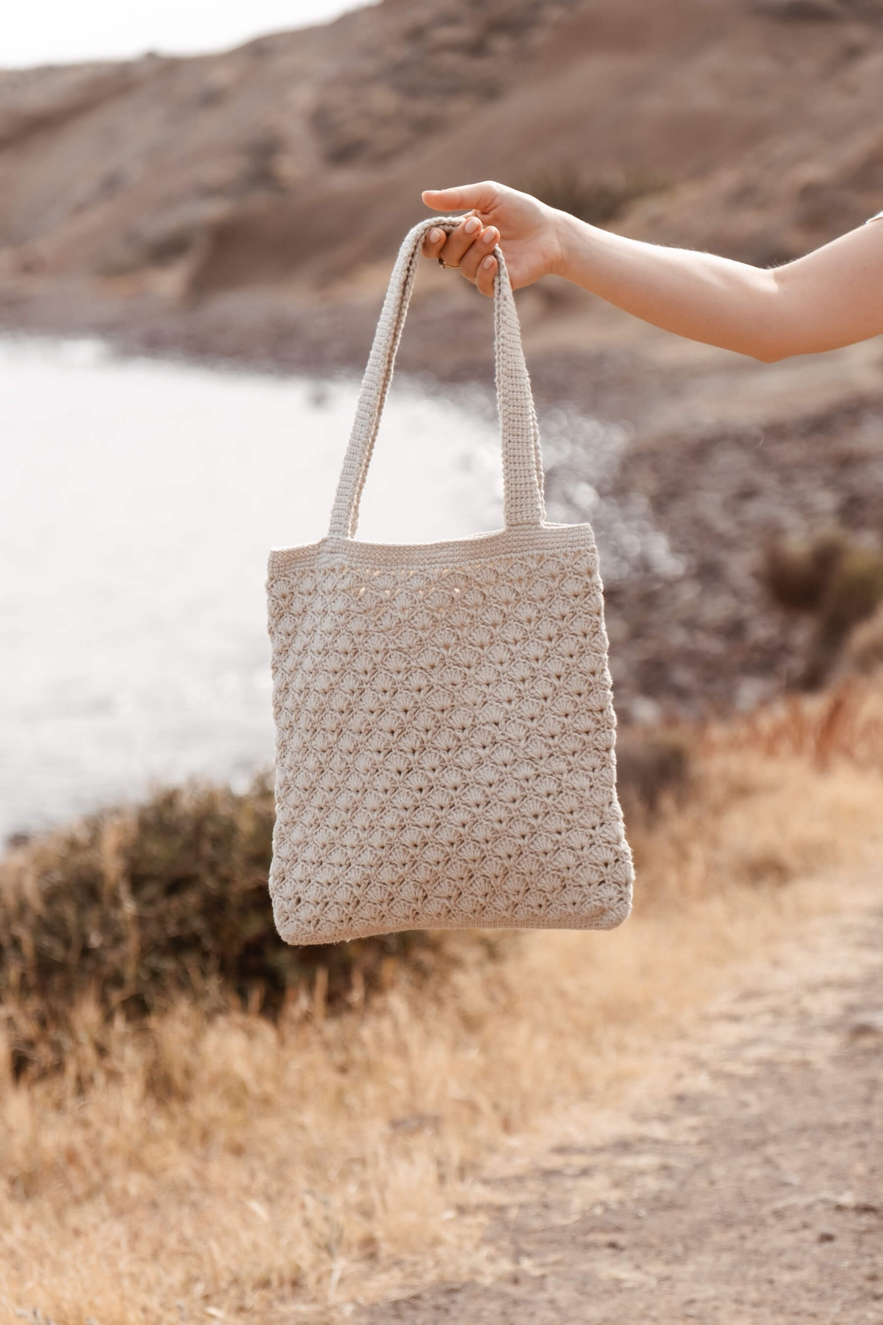 Primer plano del bolso tote SALITRE sujetado por una mano, tejido artesanal con textura de crochet en tono beige claro