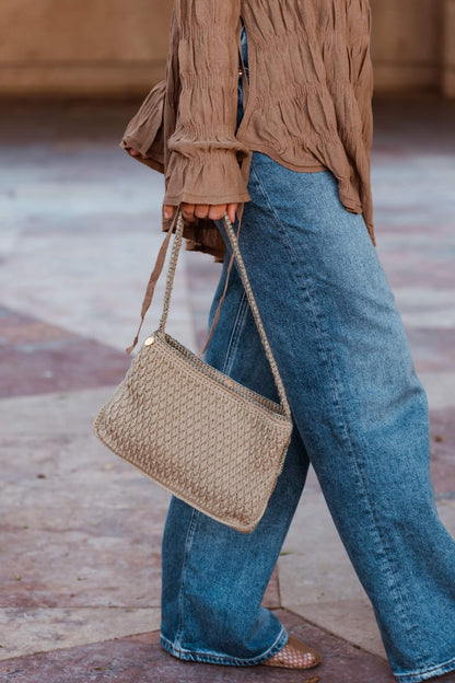Mujer con bolso artesanal Cabori Pita en crochet color arena con detalles en verde y dorado, hecho a mano en Almería, bolso minimal y versátil para el día a día.