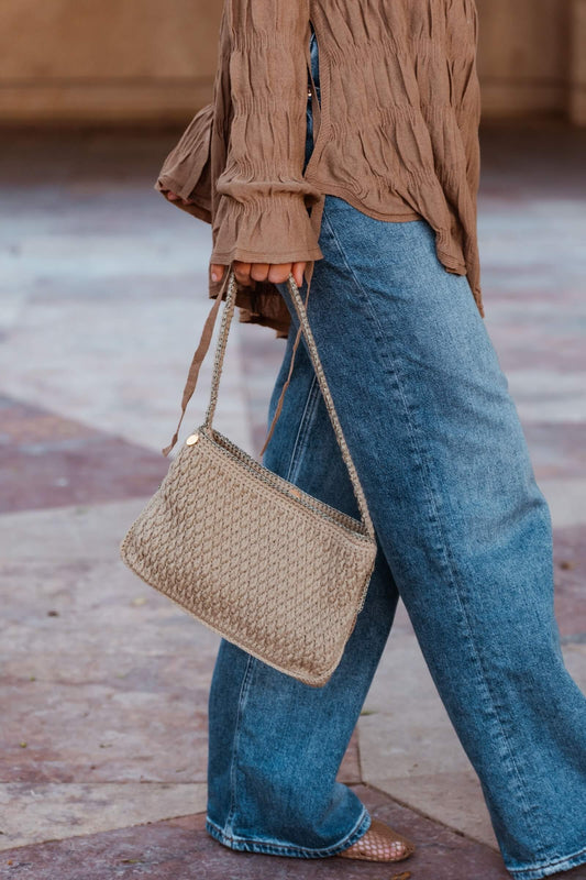 Mujer con bolso artesanal Cabori Pita en crochet color arena con detalles en verde y dorado, hecho a mano en Almería, bolso minimal y versátil para el día a día.