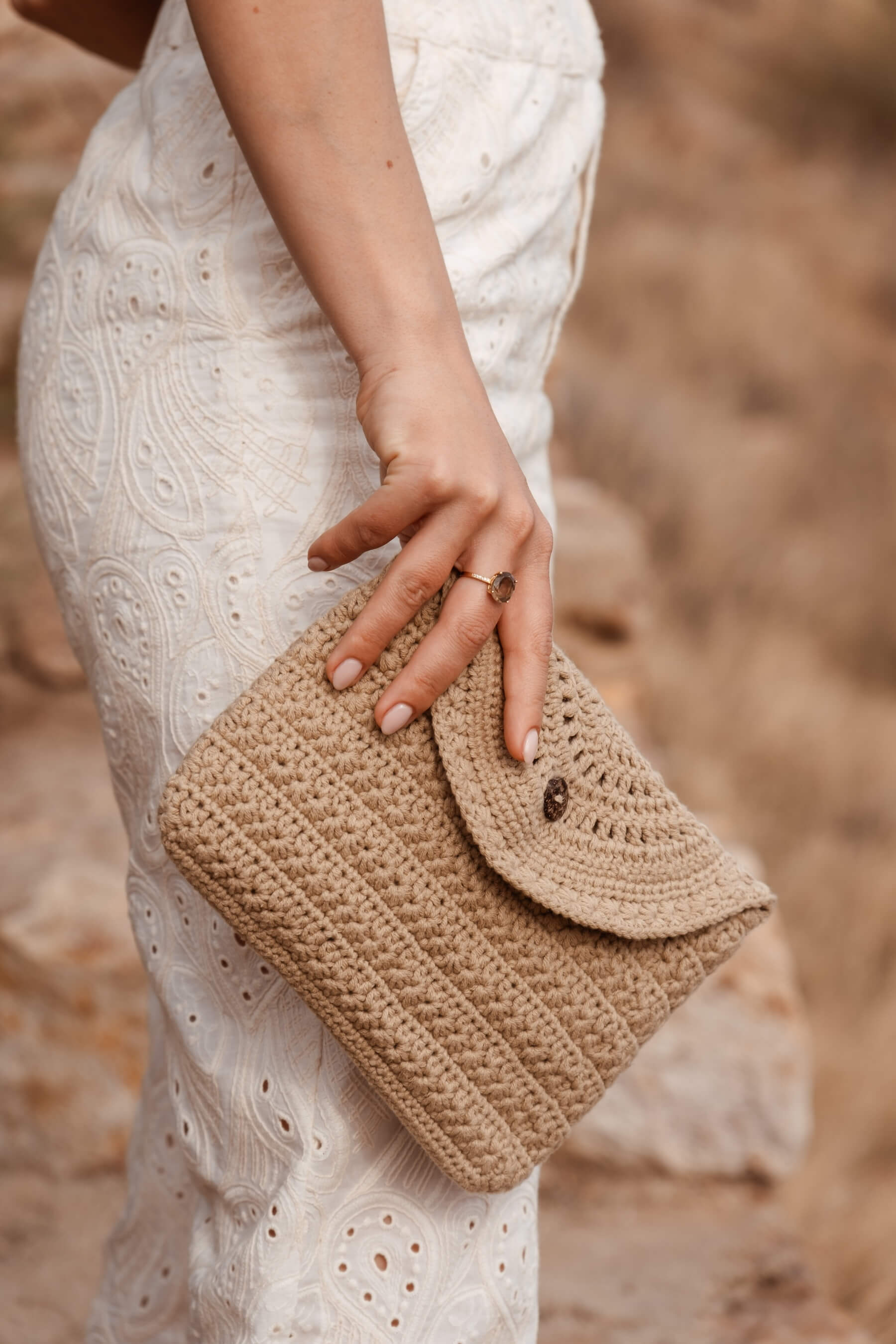 Detalle en movimiento del neceser CALIMA de crochet, con cierre de solapa y botón de coco natural