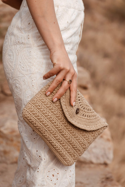 Detalle en movimiento del neceser CALIMA de crochet, con cierre de solapa y botón de coco natural