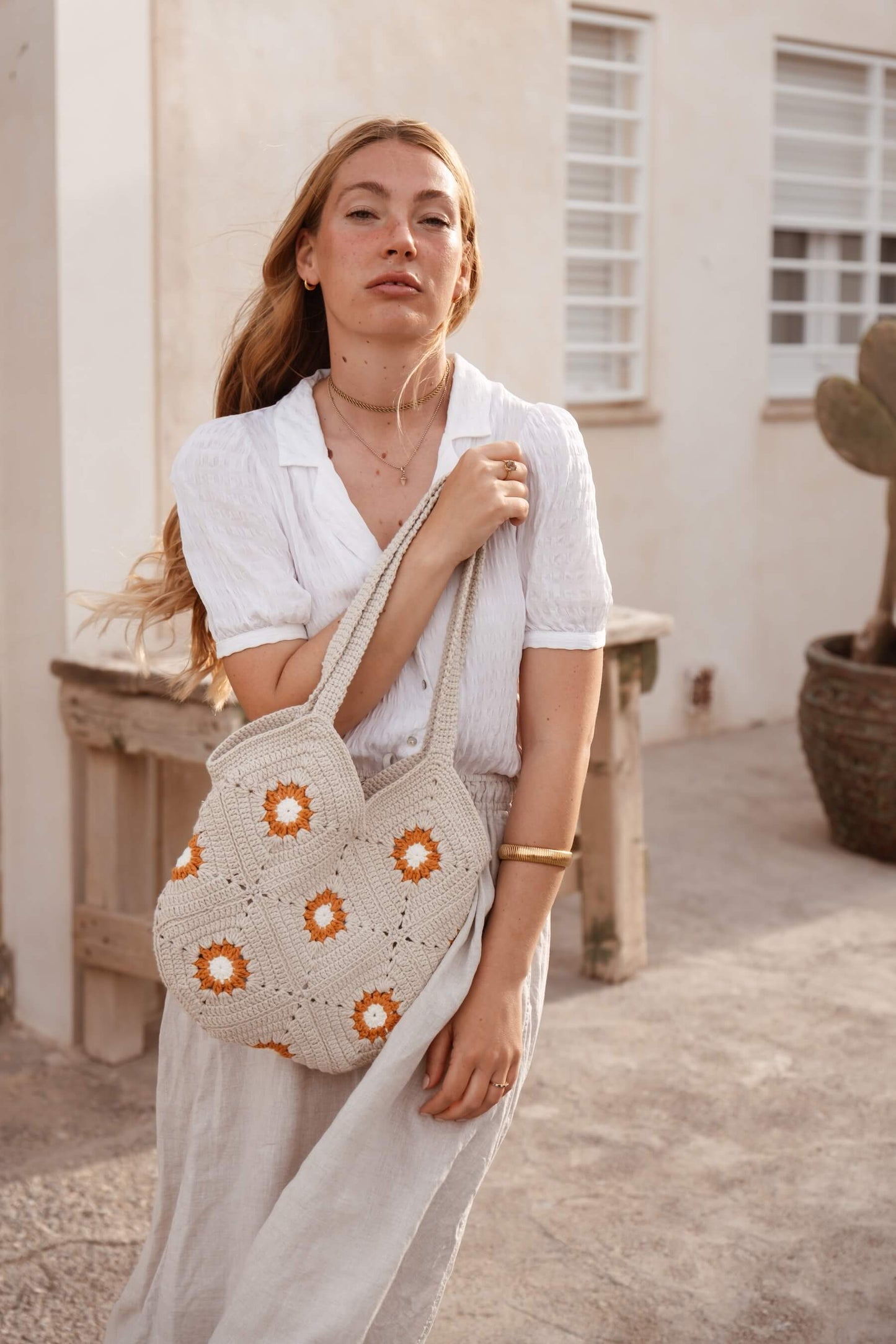 Mujer con bolso SOLANO de crochet tipo granny, diseño artesanal inspirado en los atardeceres mediterráneos