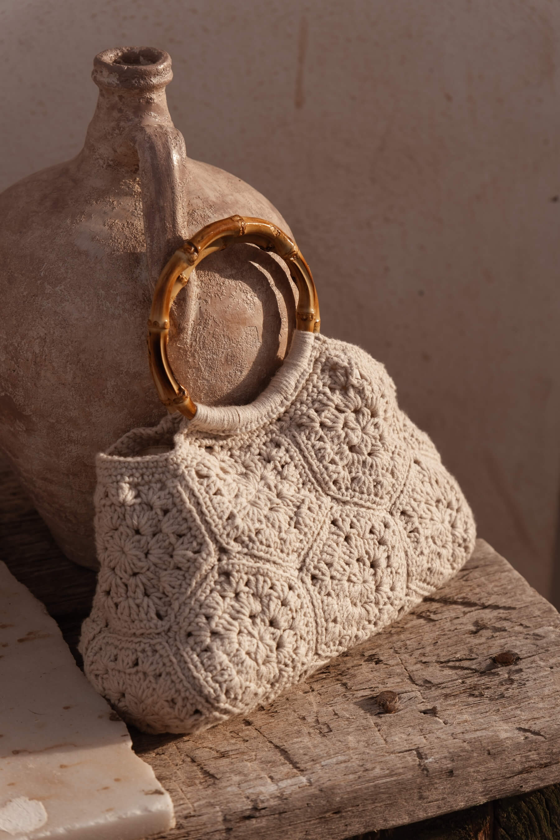 Detalle del bolso BRUMA sobre piedra, mostrando textura de crochet floral y asas de bambú natural