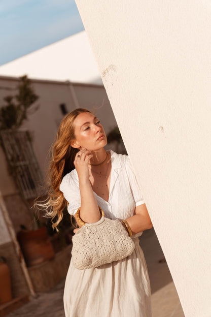 Vista lateral del bolso BRUMA, diseño artesanal en tono beige claro con patrón floral y asa de bambú