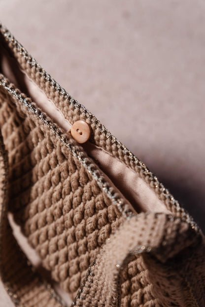 Plano cercano de bolso Pita de Cabori, hecho a mano en crochet color arena, con detalles en verde y dorado, estilo minimal versátil para cualquier ocasión.