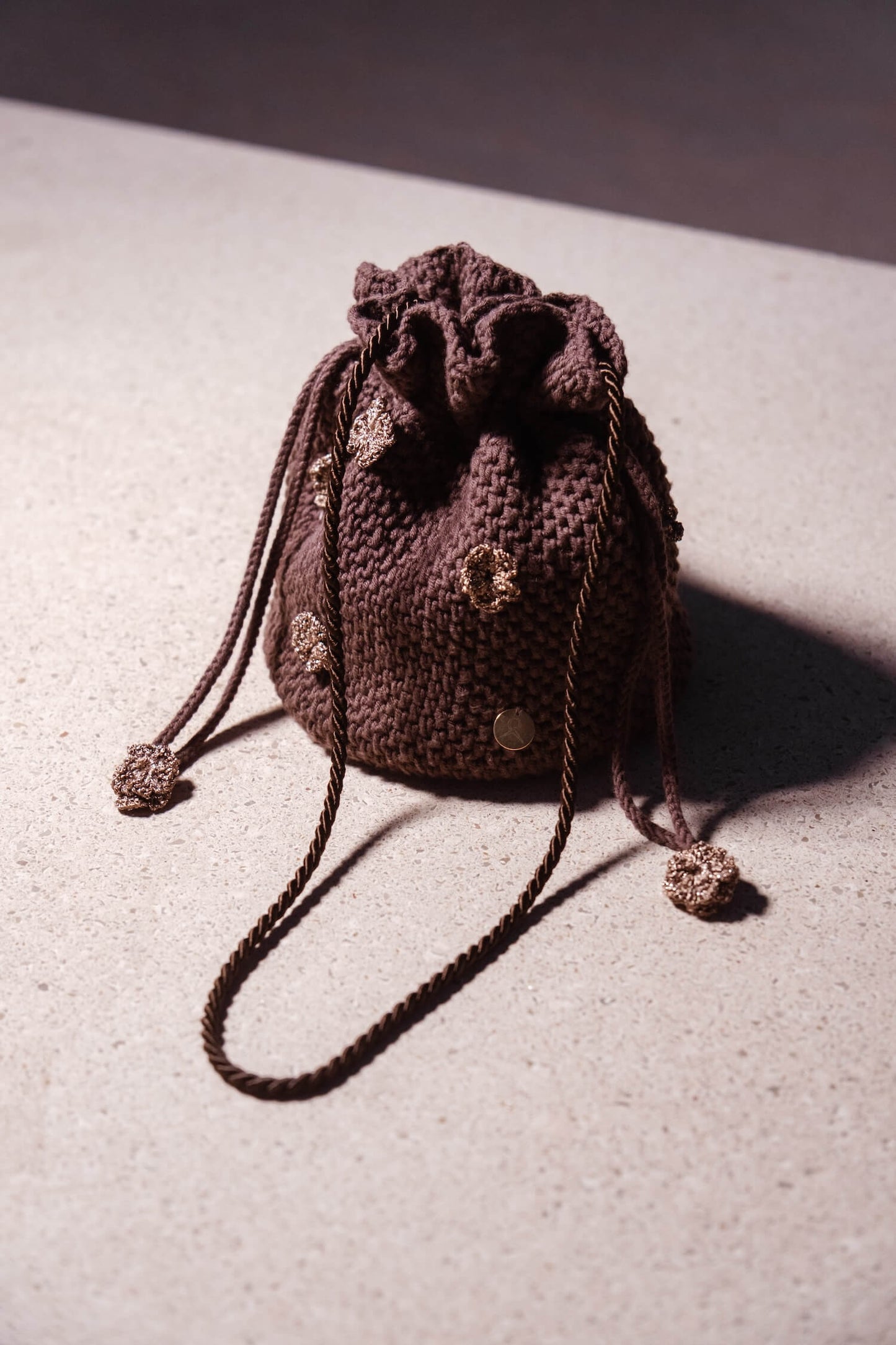 Bolso bombonera artesanal Cabori Cactus en crochet color chocolate con apliques florales y cierre de cordón, hecho a mano en Almería, ideal para invitada.