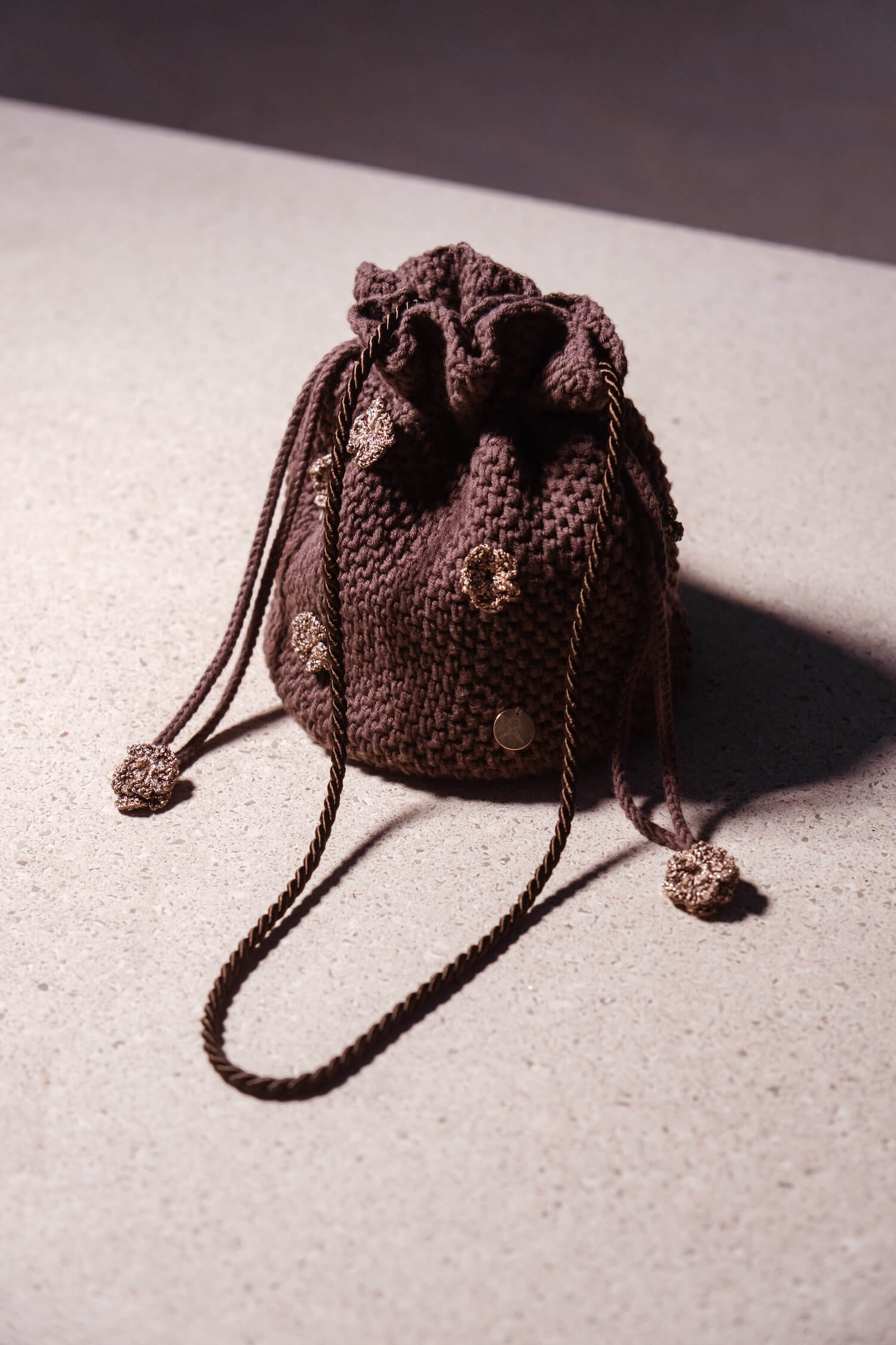 Bolso bombonera artesanal Cabori Cactus en crochet color chocolate con apliques florales y cierre de cordón, hecho a mano en Almería, ideal para invitada.